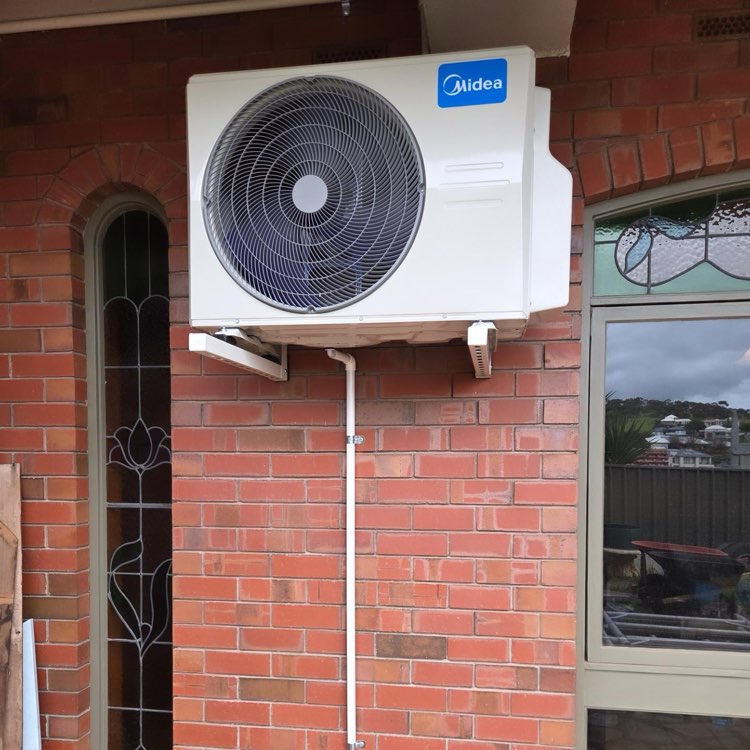Midea outdoor unit installed on a red brick wall